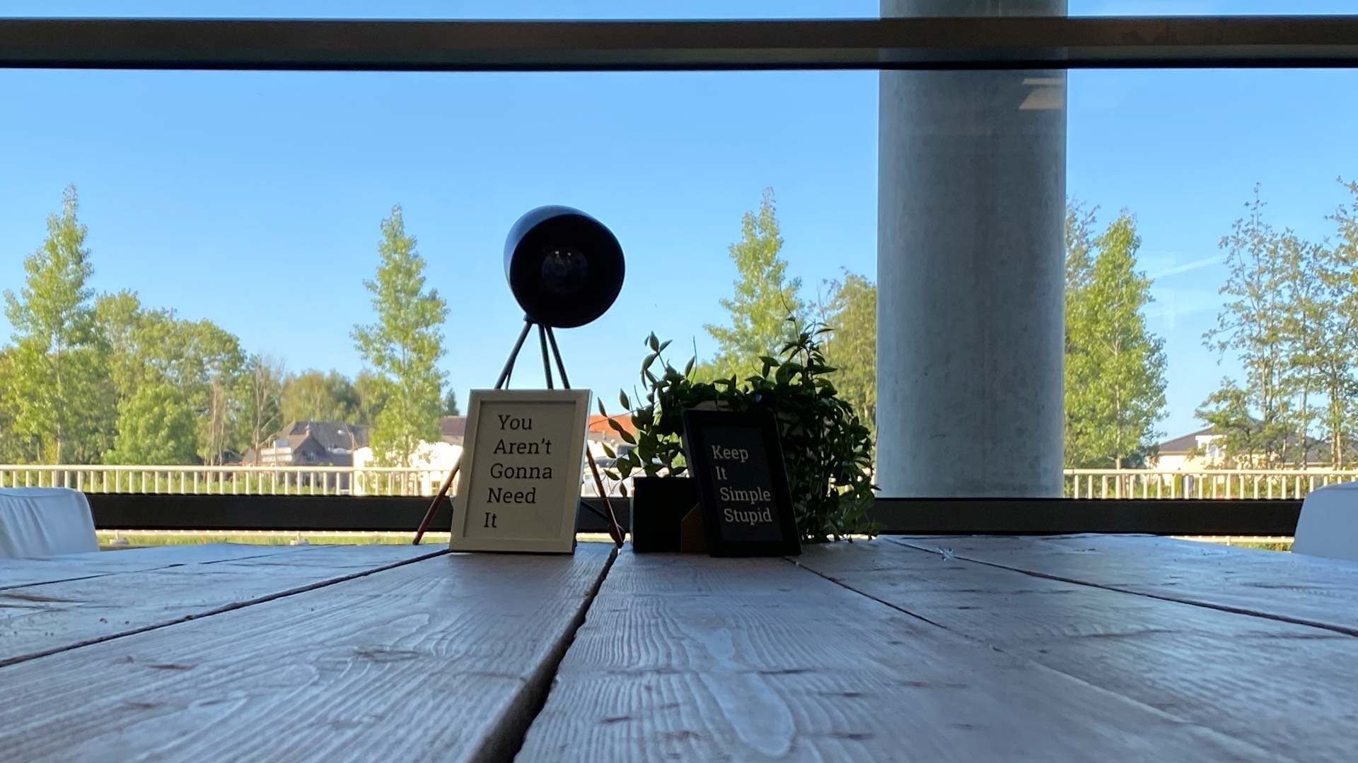 Houten vergadertafel met lamp en tekstbordjes voor een raam met uitzicht op bomen