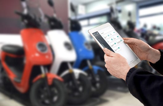Monteur bekijkt de serviceapp op een tablet bij een rij elektrische scooters