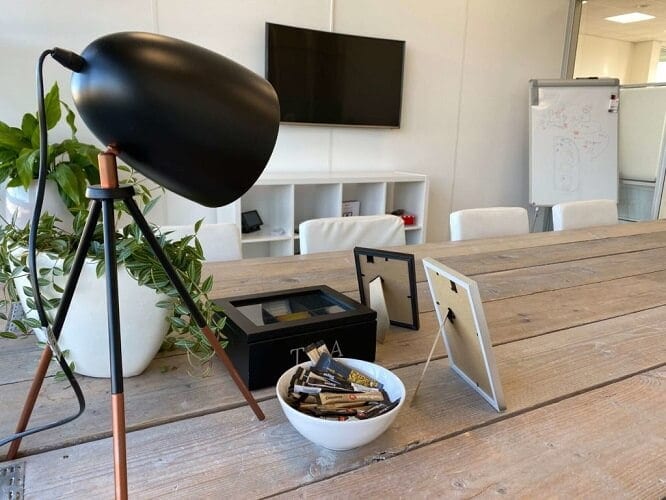 Vergaderruimte van SQUARE Concepts met houten tafel, lamp en whiteboard