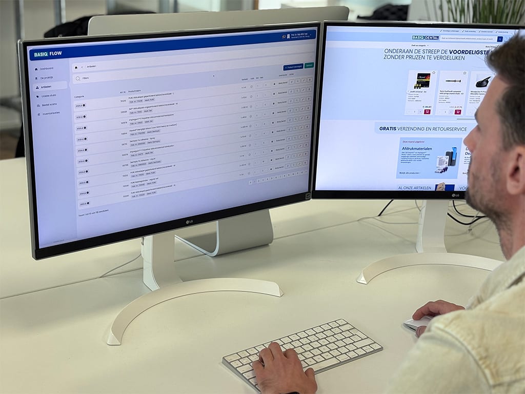 Medewerker werkt op twee schermen met het Basiq Flow-dashboard en de webshop van Basiq Dental