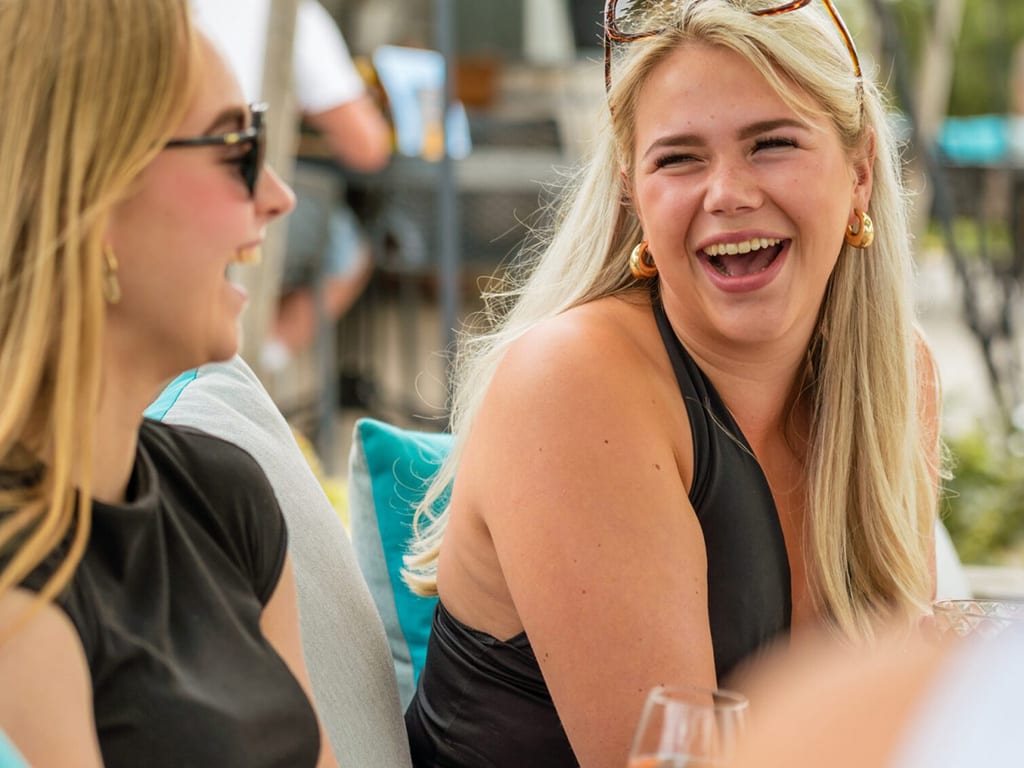 Twee lachende vrouwen op het terras op een zomerse dag