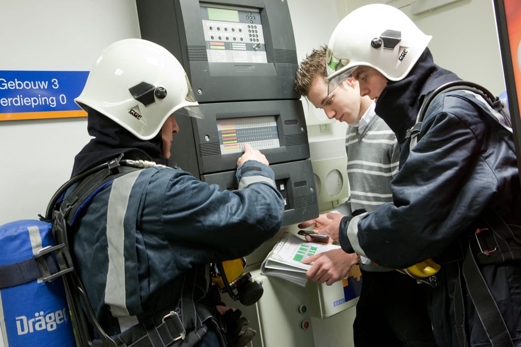Brandweerlieden en inspecteurs controleren een brandmeldcentrale